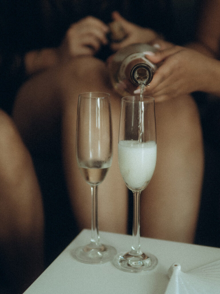 Bride pouring champagne to enjoy while getting ready